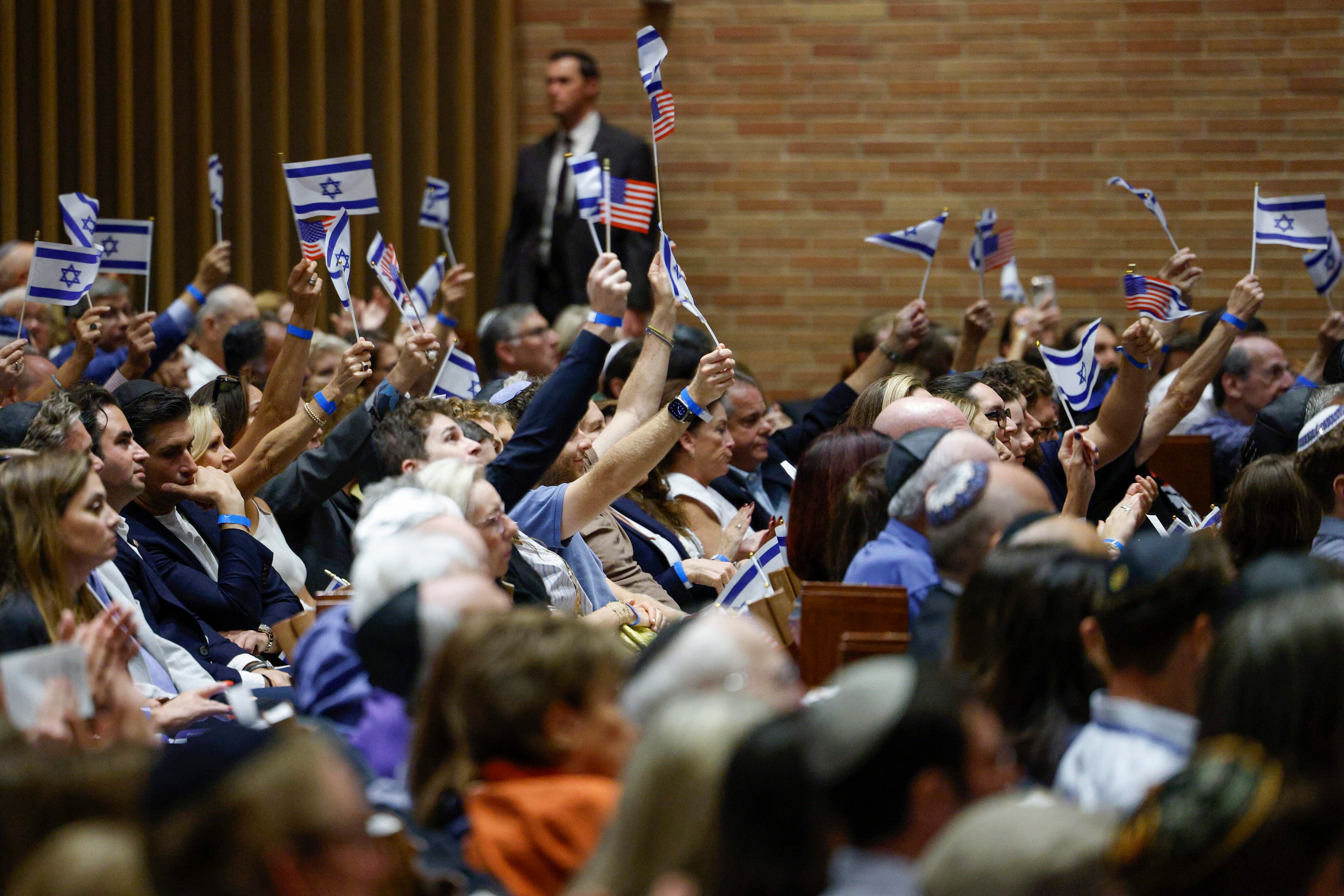 People wave Israeli and American flags after a video message from former George W. Bush...