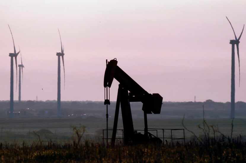 An oil well pumpjack in front of wind turbines at BP's Trinity Hills Wind Farm near Olney.