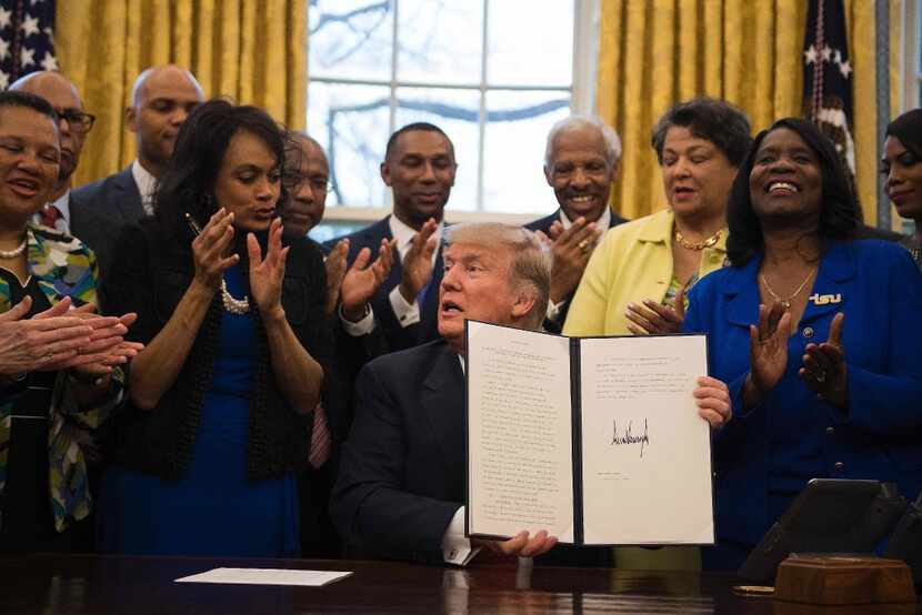 President Donald Trump holds up an executive order to bolster historically black colleges...