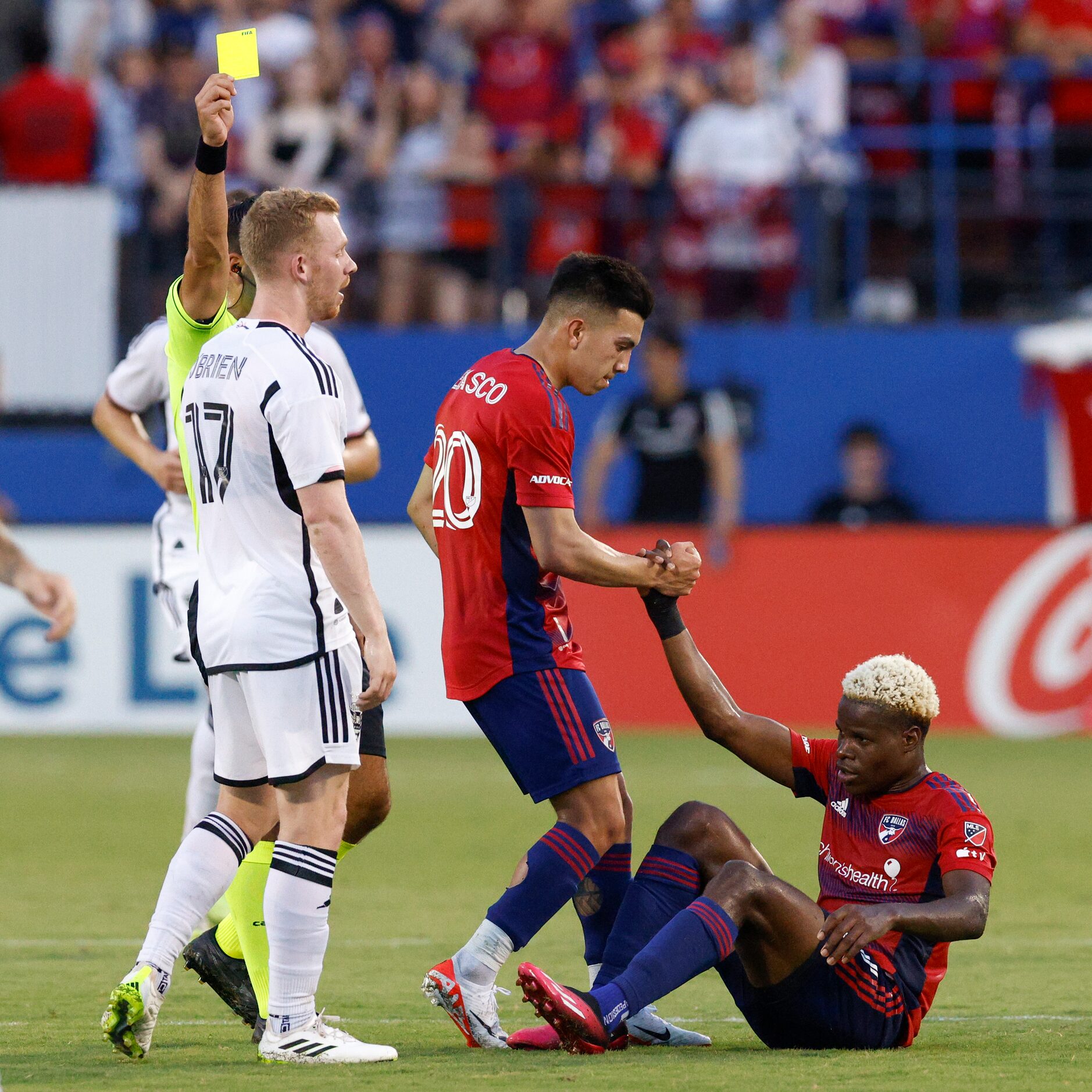 D.C. United midfielder Lewis O'Brien (17) is shown a yellow card as FC Dallas forward Alan...