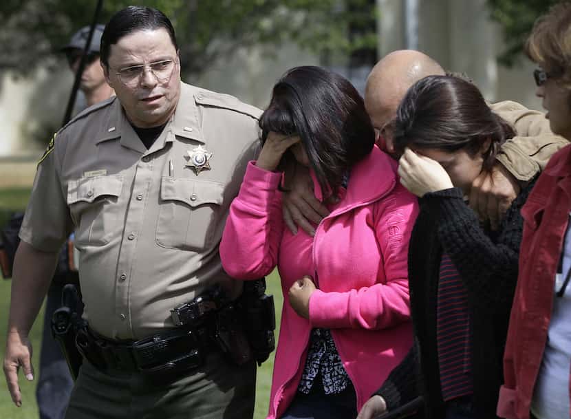 A member of the Glenn County Sheriff's Department escorts distraught people from Memorial...