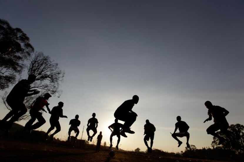 South Africans jump during a soccer training on an open field at a squatter camp in Soweto,...