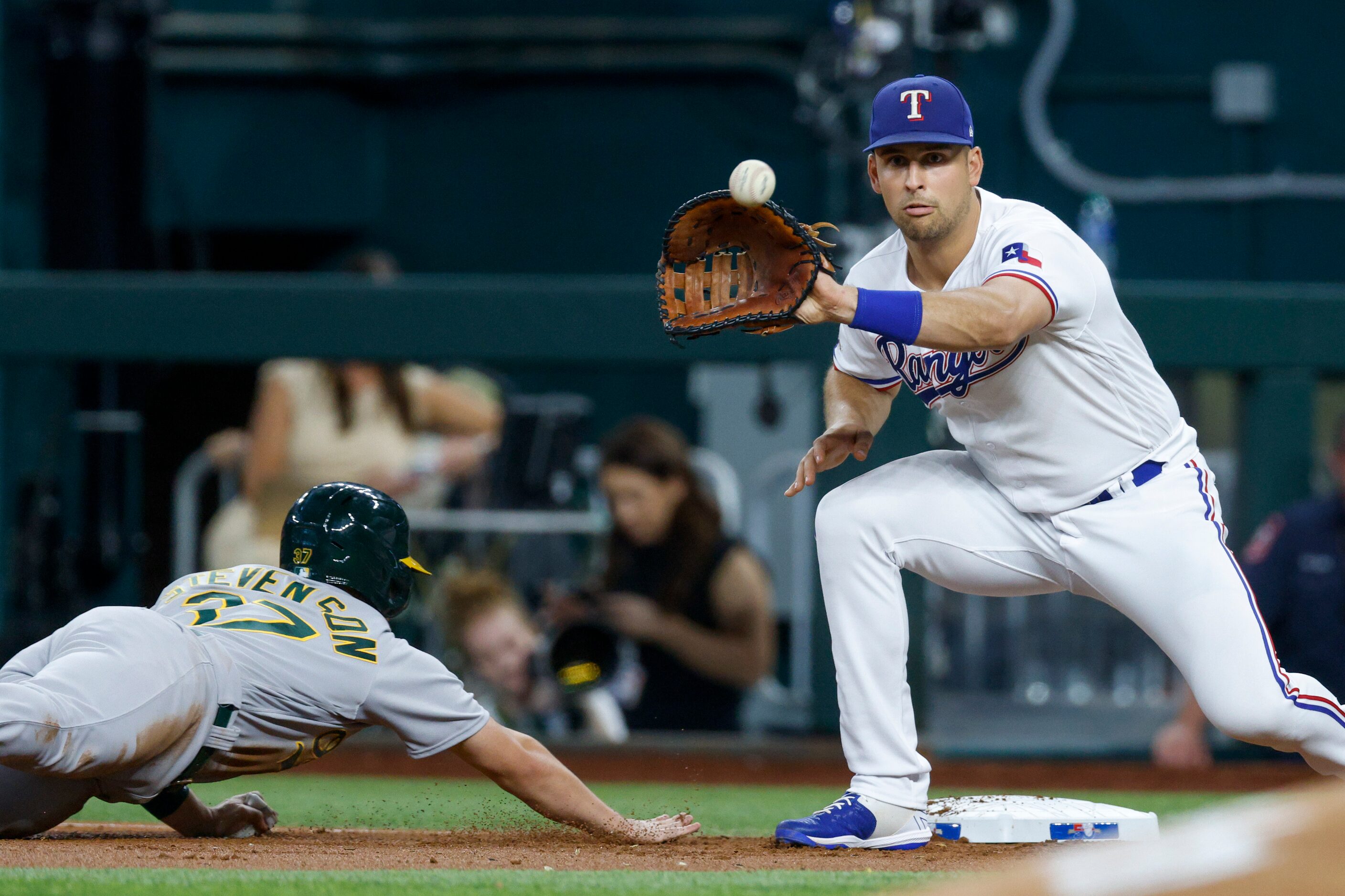 Texas Rangers first baseman Nathaniel Lowe (30) fields the ball as Oakland Athletics center...