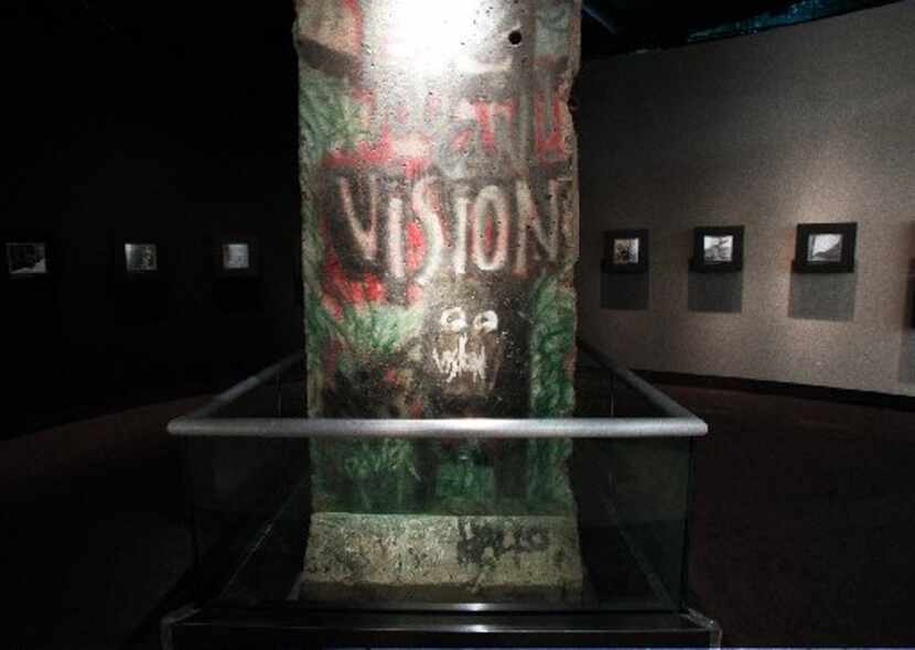 A piece of the Berlin Wall inscribed  with the word 'VISION' painted on it stands on display...