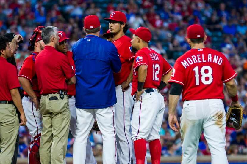 Texas Rangers starting pitcher Yu Darvish (11) talks trainers on the mound during the fifth...