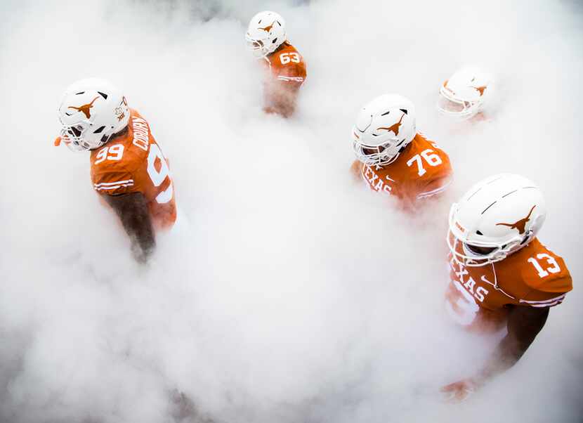 Members of the Texas Longhorns football team walk through smoke to enter the stadium before...