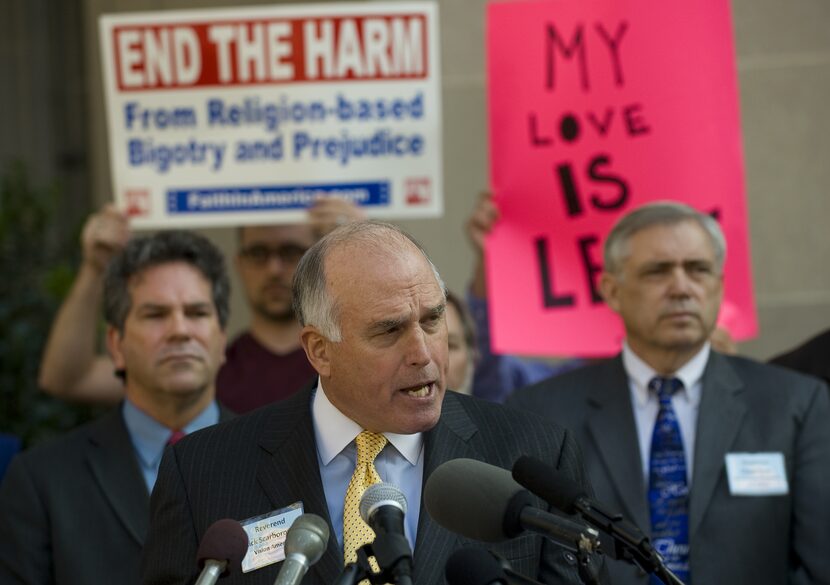 Gay rights activists hold placards in the background as Minister Rick Scarborough (middle)...