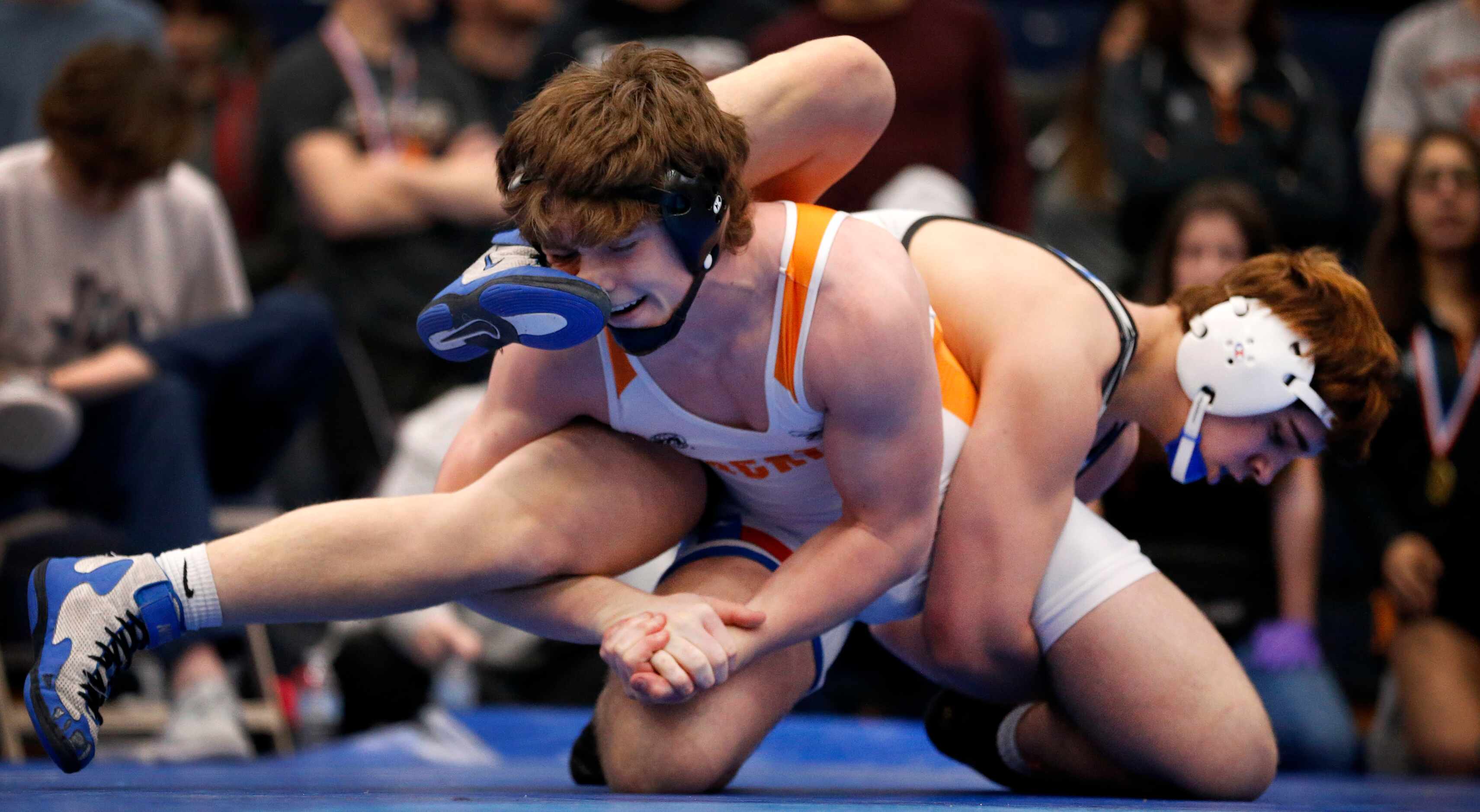 Rockwall High wrestler Bryce Milster (facing) takes a foot to the nose by Plano West's Plano...