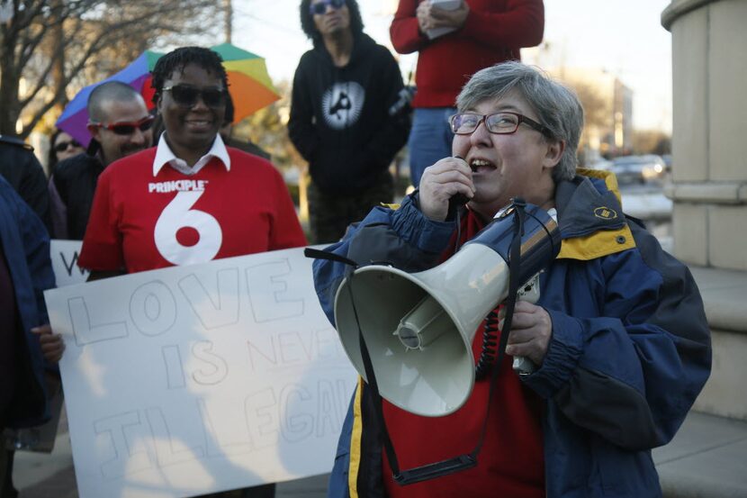 CD Kirven holds a sign as Patti Fink, with the Dallas Gay and Lesbian Alliance, speaks about...