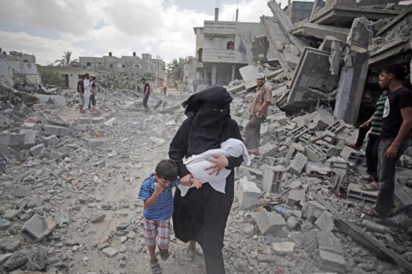 
Rescuers inspected the rubble of destroyed houses as Palestinians walked through the Rafah...