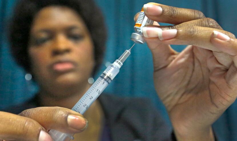 A health care worker prepares to administer an immunization at the Dallas Mayor's Back to...