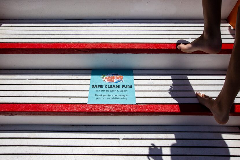 Social distancing reminders line the staircase as customers climb up to a water attraction...