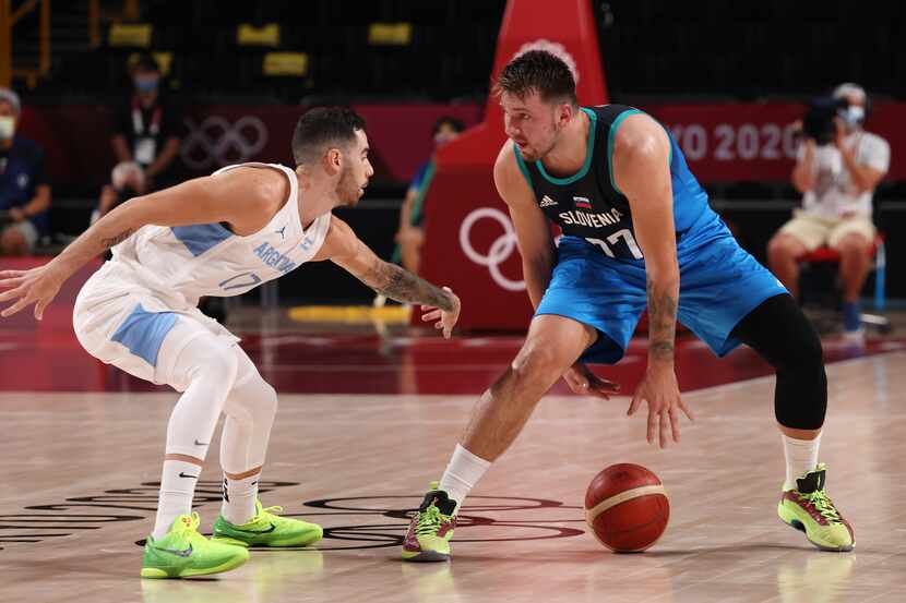 Slovenia’s Luka Doncic (77) dribbles between his legs as he is defended by Argentina’s Luca...