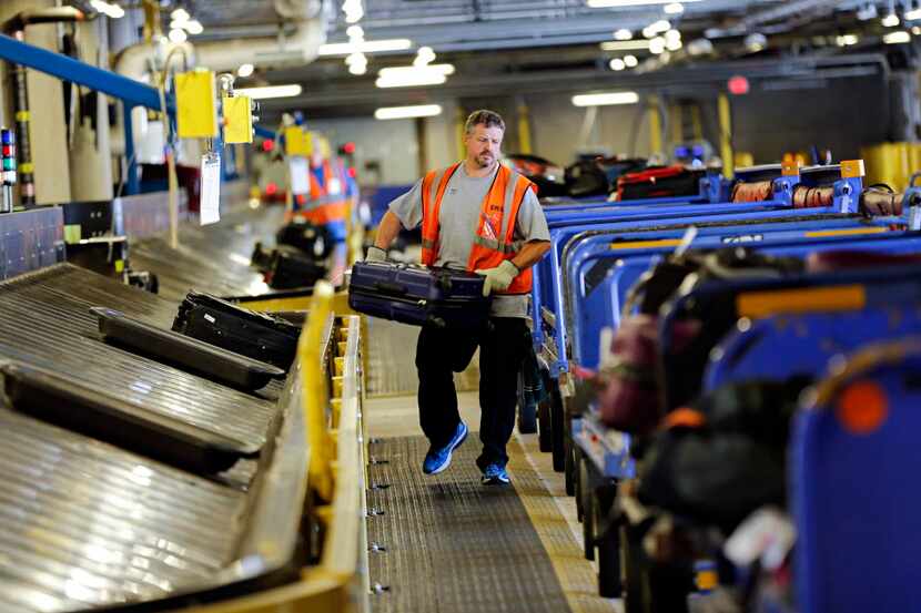  Southwest Airlines ramp agent Matt Lockby carries luggage in the baggage sorting area at...