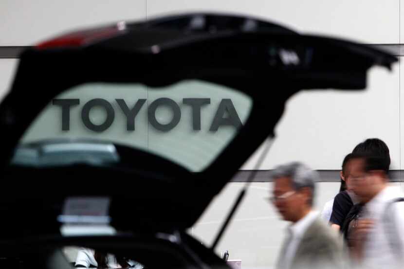 FILE - In this Aug. 2, 2011 file photo, people walk by a car on display at Toyota's Tokyo,...