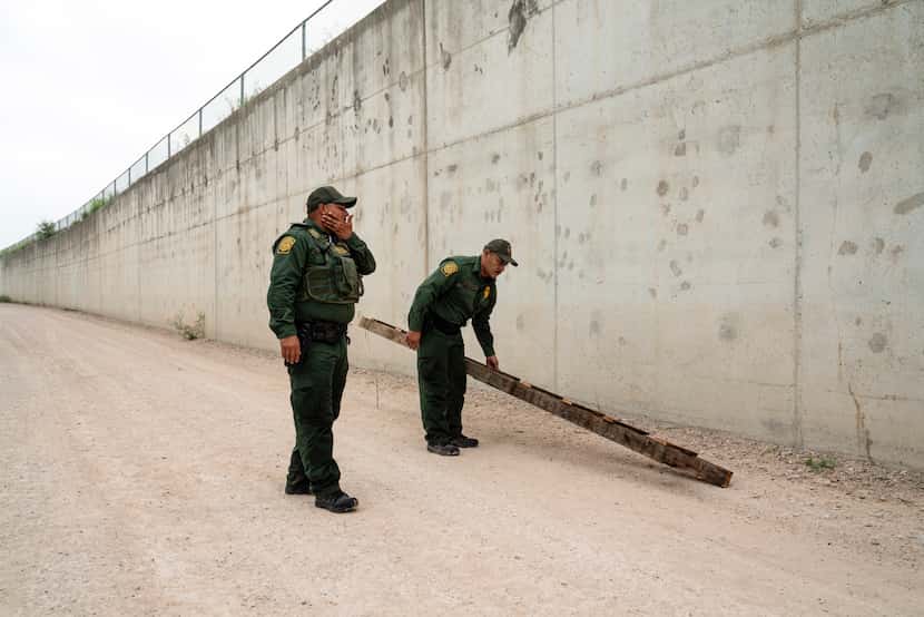 FILE - U.S. Border Patrol agents pick up a ladder that migrants carried to the border wall...