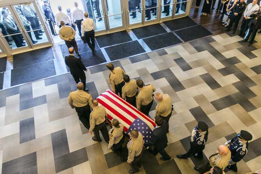 Pallbearers escort the casket of Travis County sheriff's Sgt. Craig Hutchinson's after his...
