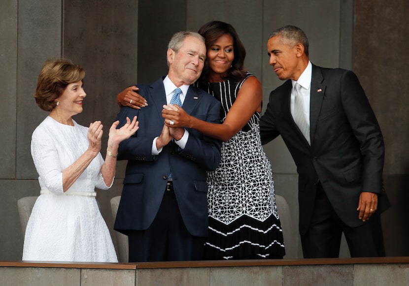 First lady Michelle Obama (center) hugs former President George W. Bush, as President Barack...