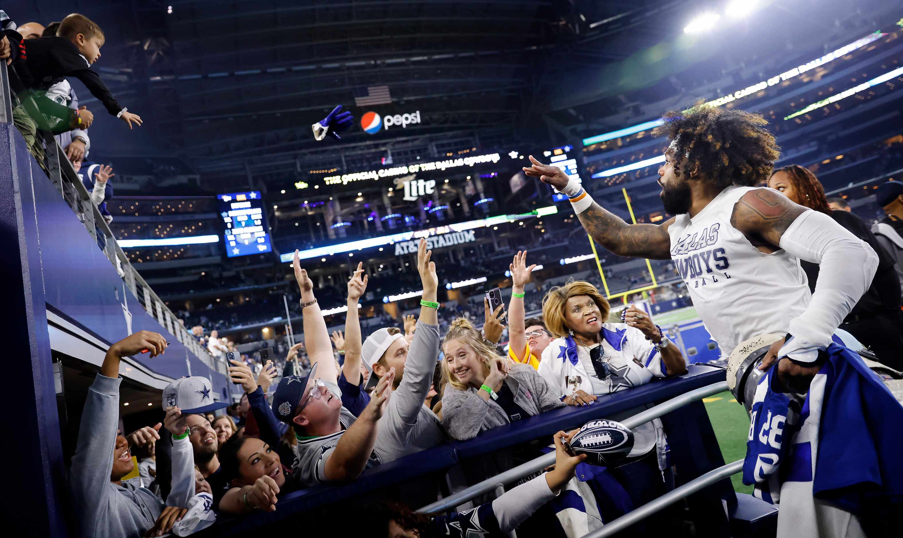 Dallas Cowboys running back Ezekiel Elliott (right) tosses his gloves to a fan following...