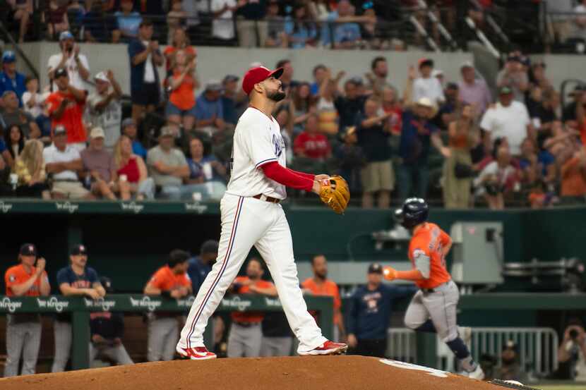 Texas Rangers starting pitcher Martin Perez, foreground, looks up at the scoreboard after...