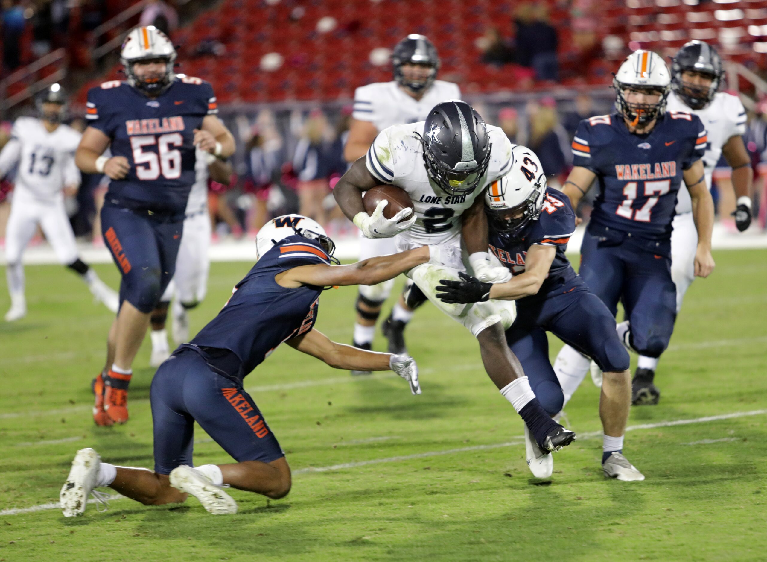 Lone Star player #2, Ashton Jeanty, is brought down by Wakeland players #1, Davion Woolen,...