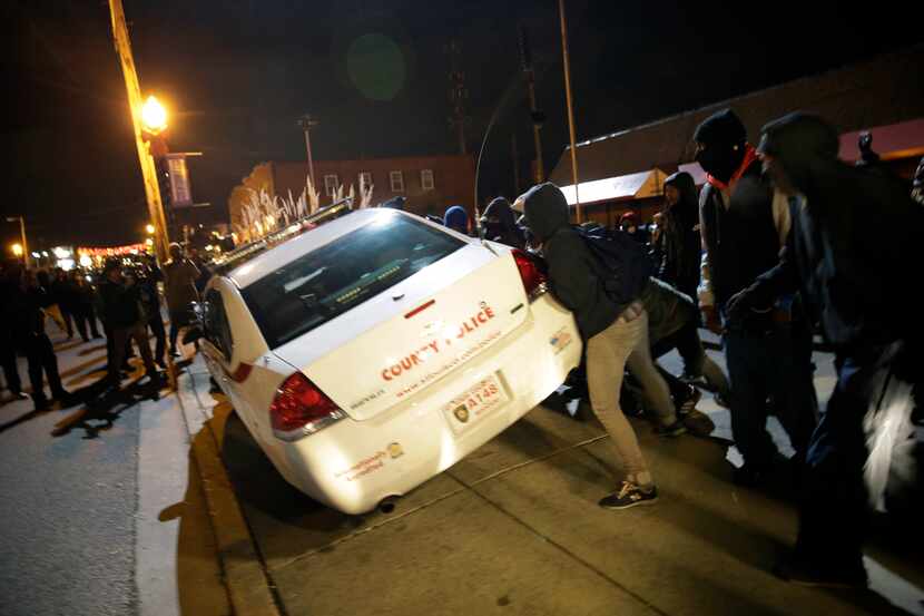 Protesters shove a police car after the announcement of the grand jury decision not to...