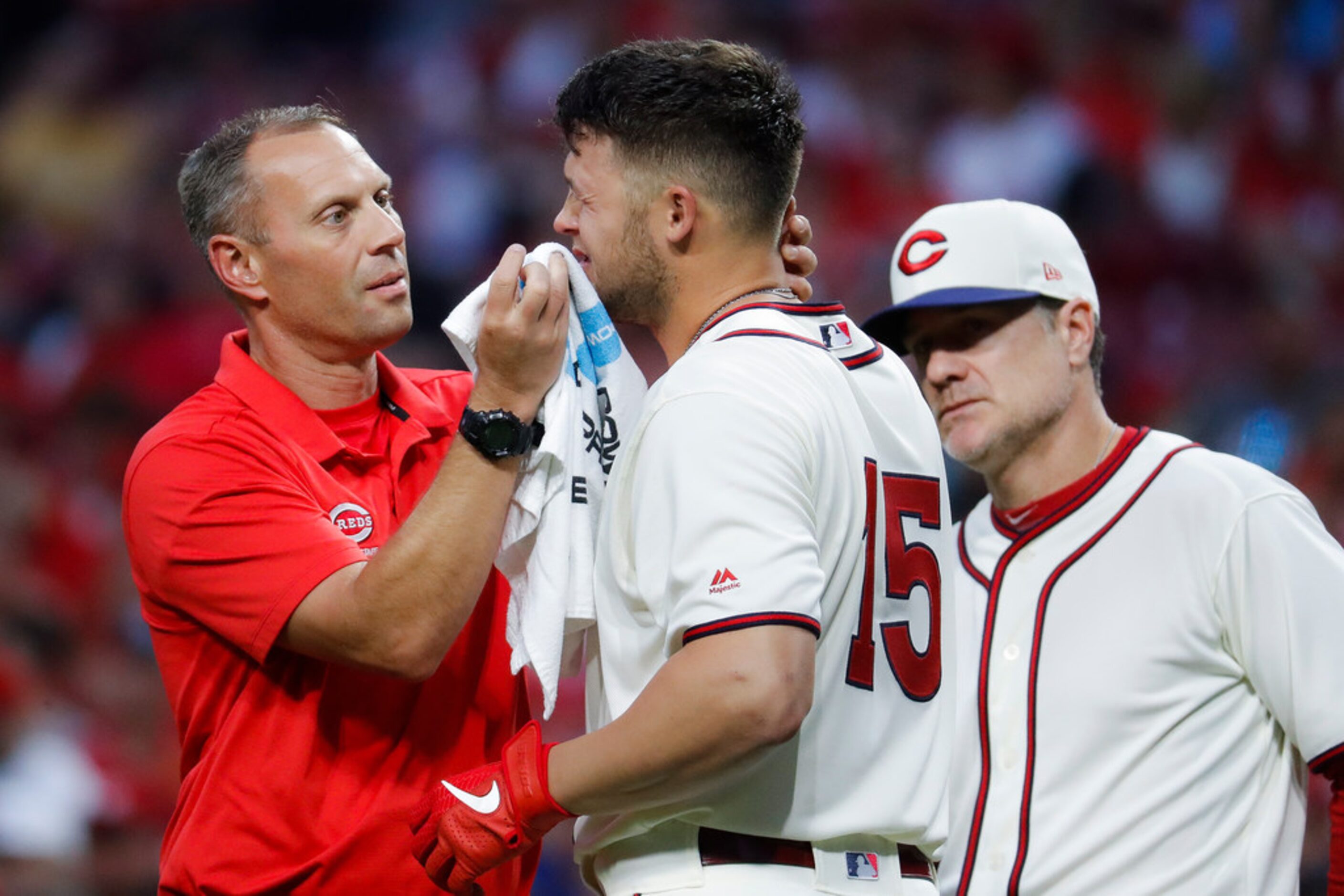 Cincinnati Reds' Nick Senzel (15) winces after taking a foul tip ball to the face during the...