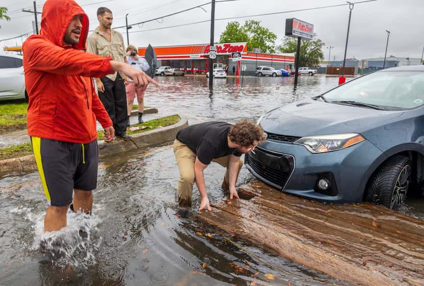Passersby help a driver move a heavy wooden platform that floated several blocks and into...