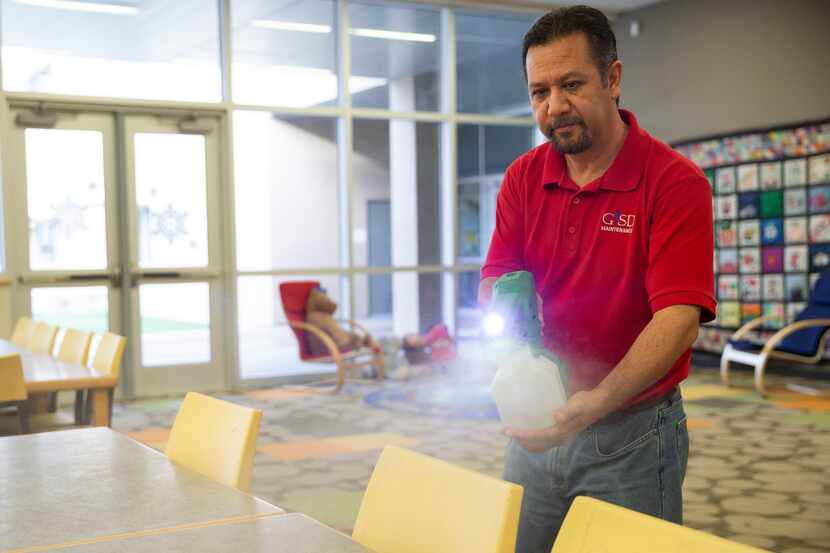 Raul Rodriguez mists the library at Daugherty Elementary School to disinfect it of any...