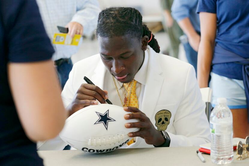 Dallas Cowboys wide receiver Lucky Whitehead (13) signs a football for a fan shortly after...