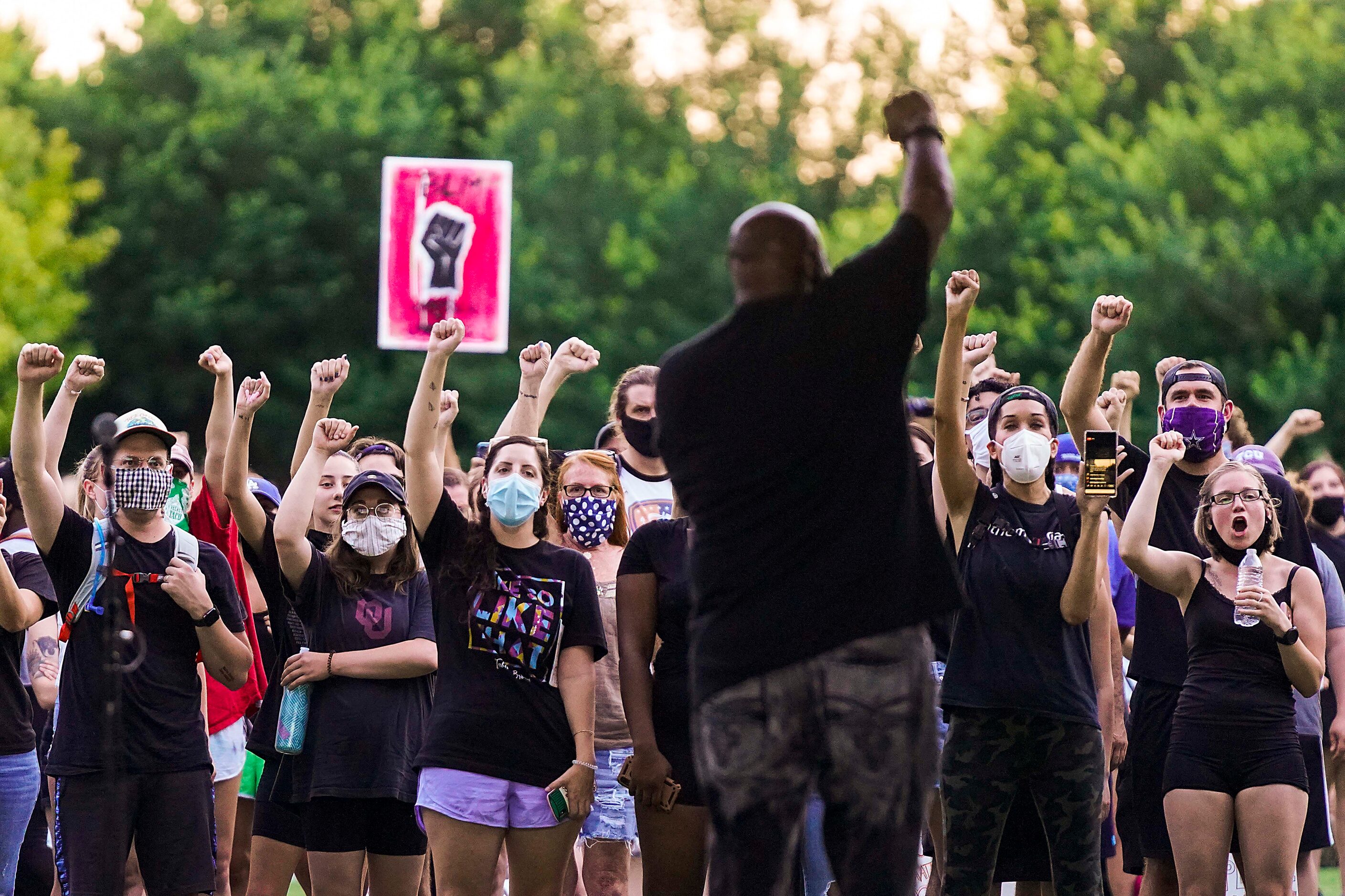 People in the crowd raise their fists along with DISD trustee Maxie Johnson as he addresses...