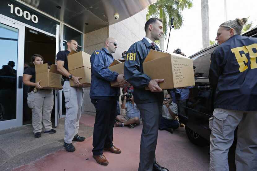 FBI agents carry boxes during a raid on May 27, 2015 in Miami Beach, Florida. (Photo by Joe...