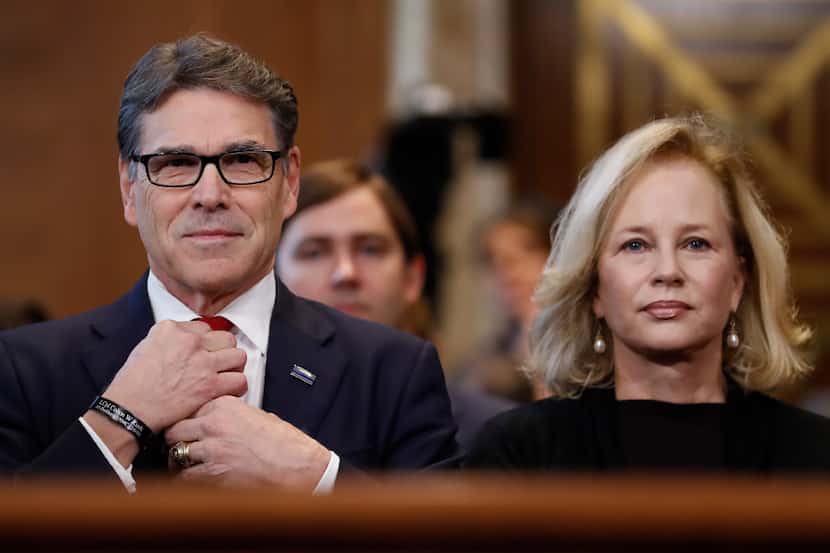 Energy Secretary-designate Rick Perry, accompanied by his wife Anita, straightens his tie...