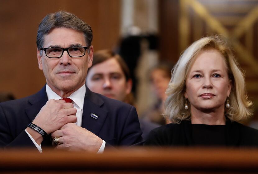 Energy Secretary-designate Rick Perry, accompanied by his wife Anita, straightens his tie...