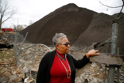 Homeowner Marsha Jackson looks over her damaged fence at the large mounds of shredded...