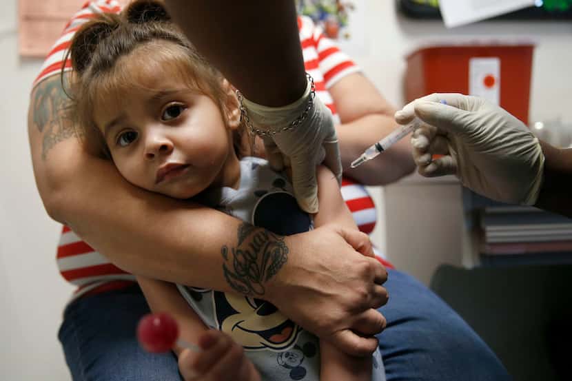Karma Islas, 2, is held by her mother Maria Islas of Dallas as she gets a shot for a vaccine...