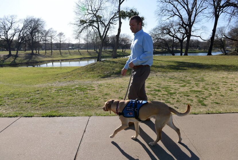 Dustin Deweerd, walks his 3-year-old Labrador service dog Gunny, at Lake Cliff Park on March...