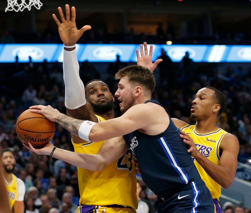 FILE - Mavericks guard Luka Doncic (77) looks to pass as he's defended by Lakers forward...