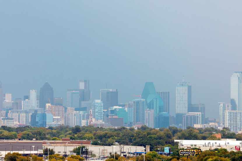 The downtown Dallas skyline is seen through rain.