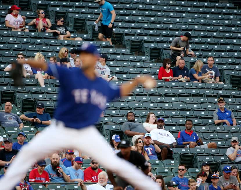 A sparse crowd watches the first pitch by Texas Rangers starting pitcher Mike Minor (36) in...