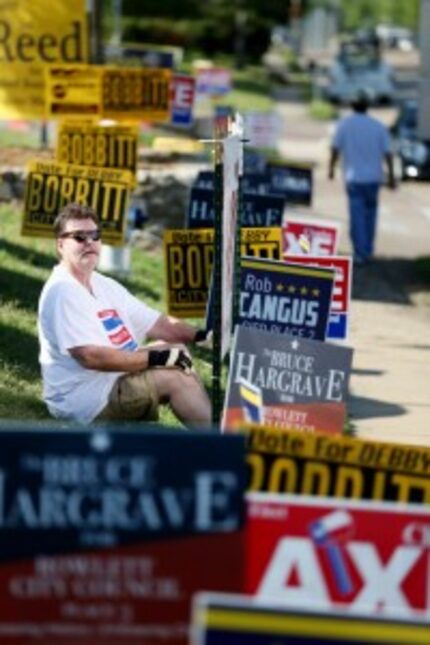  Randal Brown hangs a sign for his wife, Martha Brown, who is running for Rowlett City...