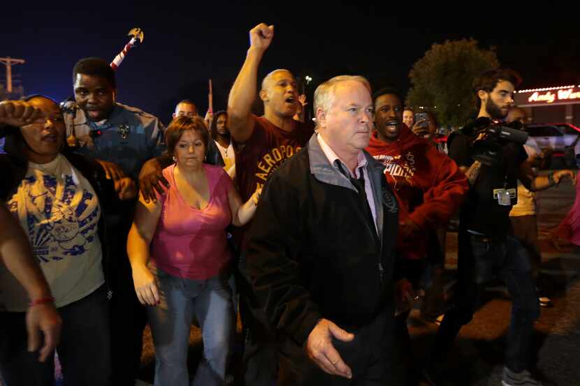 Ferguson Police Chief Tom Jackson begins to march with protesters before clashes led to...