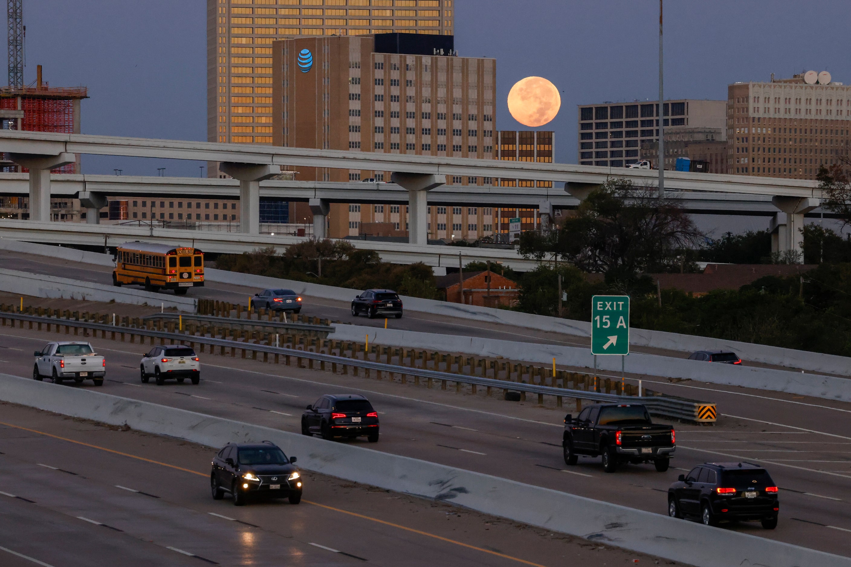 Traffic flows along Interstate 30 as a supermoon sets behind downtown Fort Worth, Thursday,...