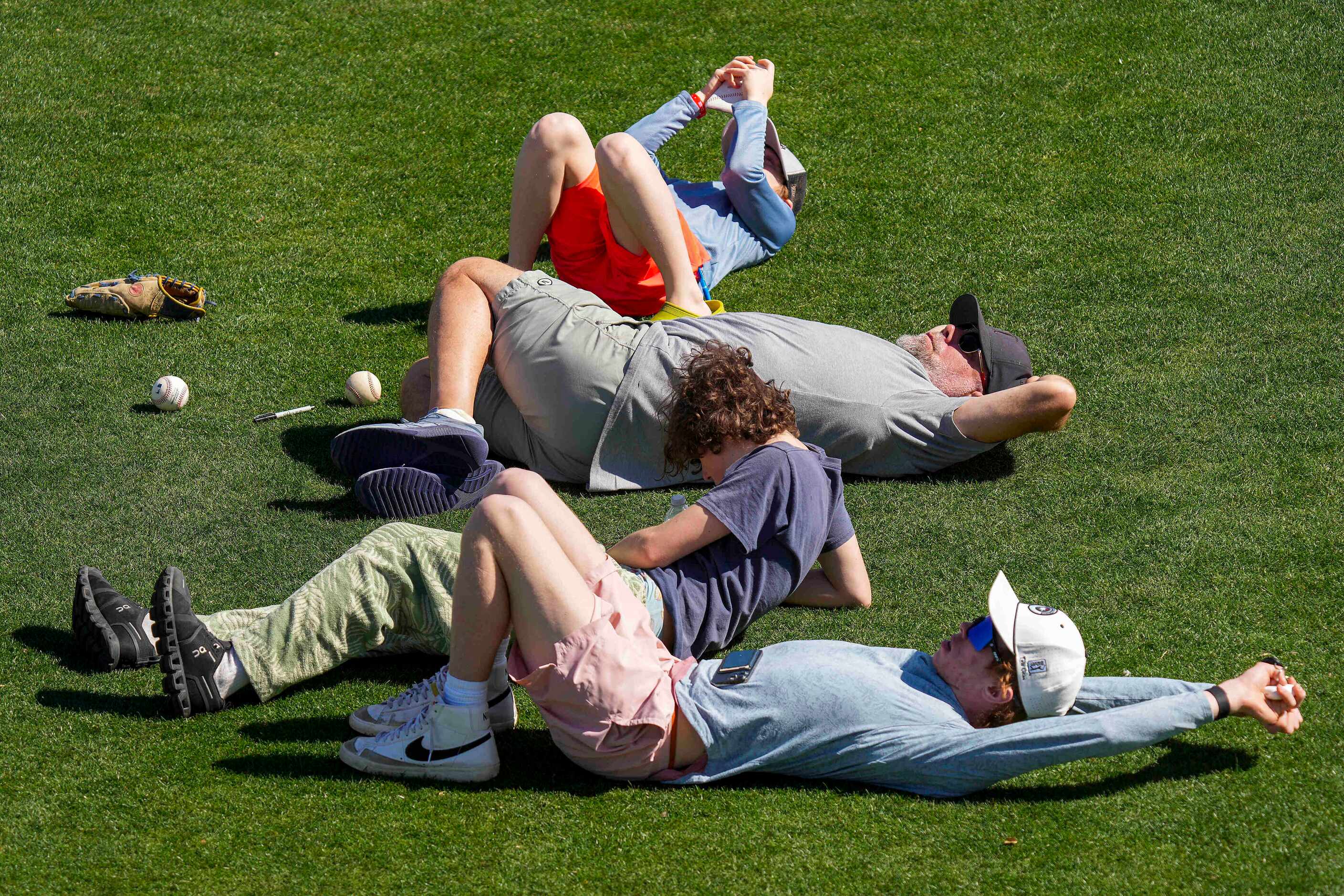 Fans relax in the sun during the Texas Rangers first full squad spring training workout at...