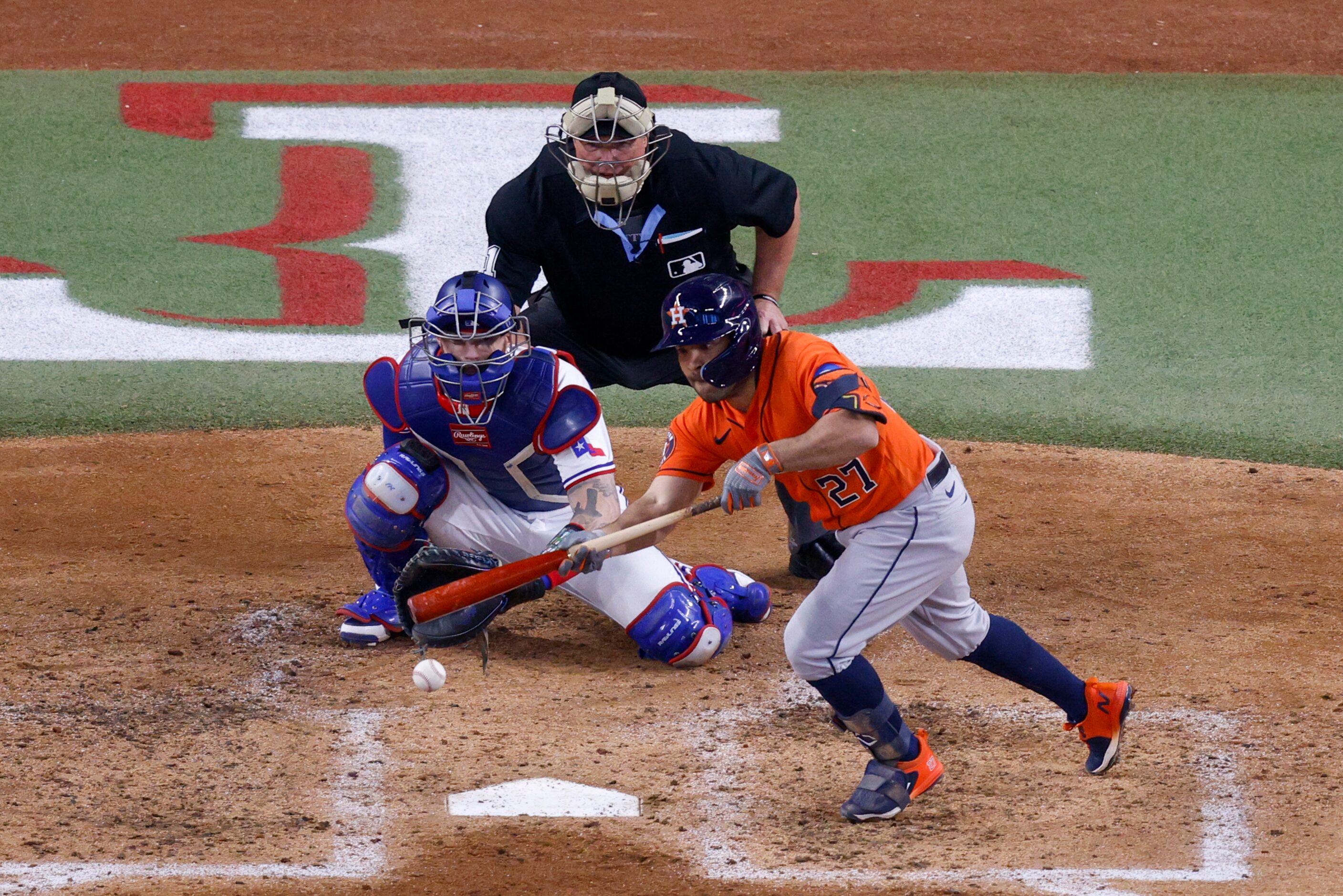 Houston Astros second baseman Jose Altuve (27) bunts the ball ahead of Texas Rangers catcher...