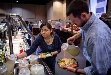 Melissa Harp (center) and Michael Wash serve themselves lunch at Pioneer Natural Resources'...