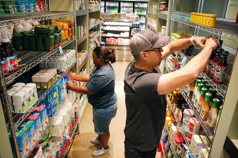 General manager Nathan Hartkopf  (right) and cashier Ozzie Massey stock shelves at the...