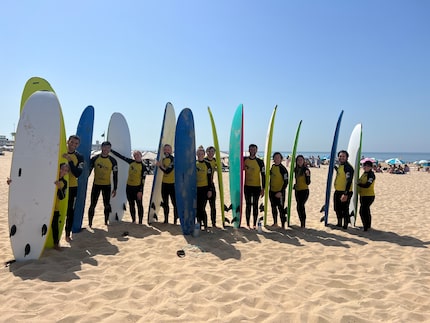 Vela Wood employees stand on a beach with surfboards.