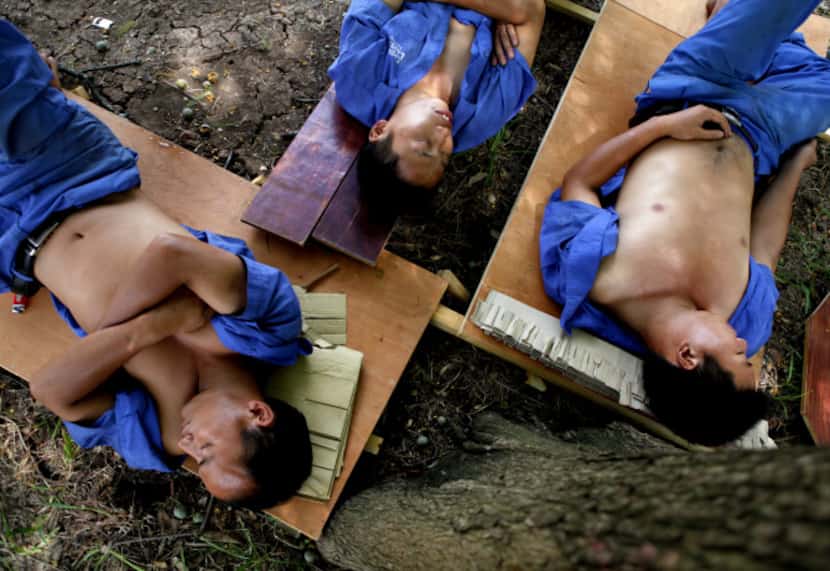 From left: Yanqing Zhang, Shunhong Song  and Shunli Song take a nap on cots they made from...