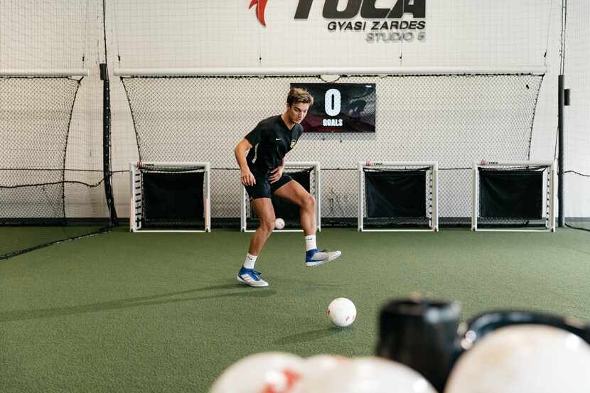 soccer player kicks ball into goals at indoor facility